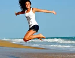 Donna che salta in riva al mare