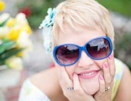 Donna che sorride con gli occhiali da sole blu