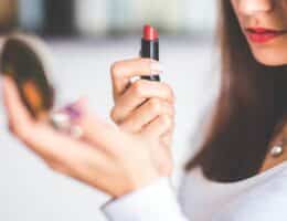 Donna che applica il rossetto rosso specchiandosi