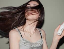 Donna con capelli lunghi neri e balsamo in mano