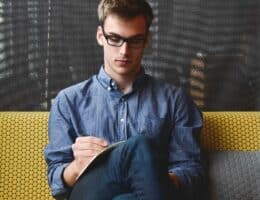 Ragazzo in posa seduto sul divano mentre legge un libro